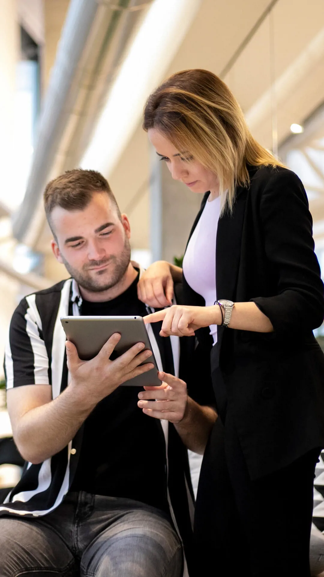 Two colleagues are looking at a tablet and talking